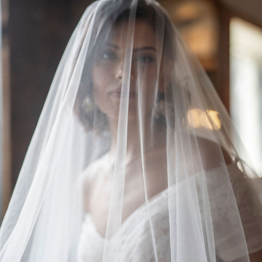 Woman in a wedding dress with a veil and bouquet, blurred background