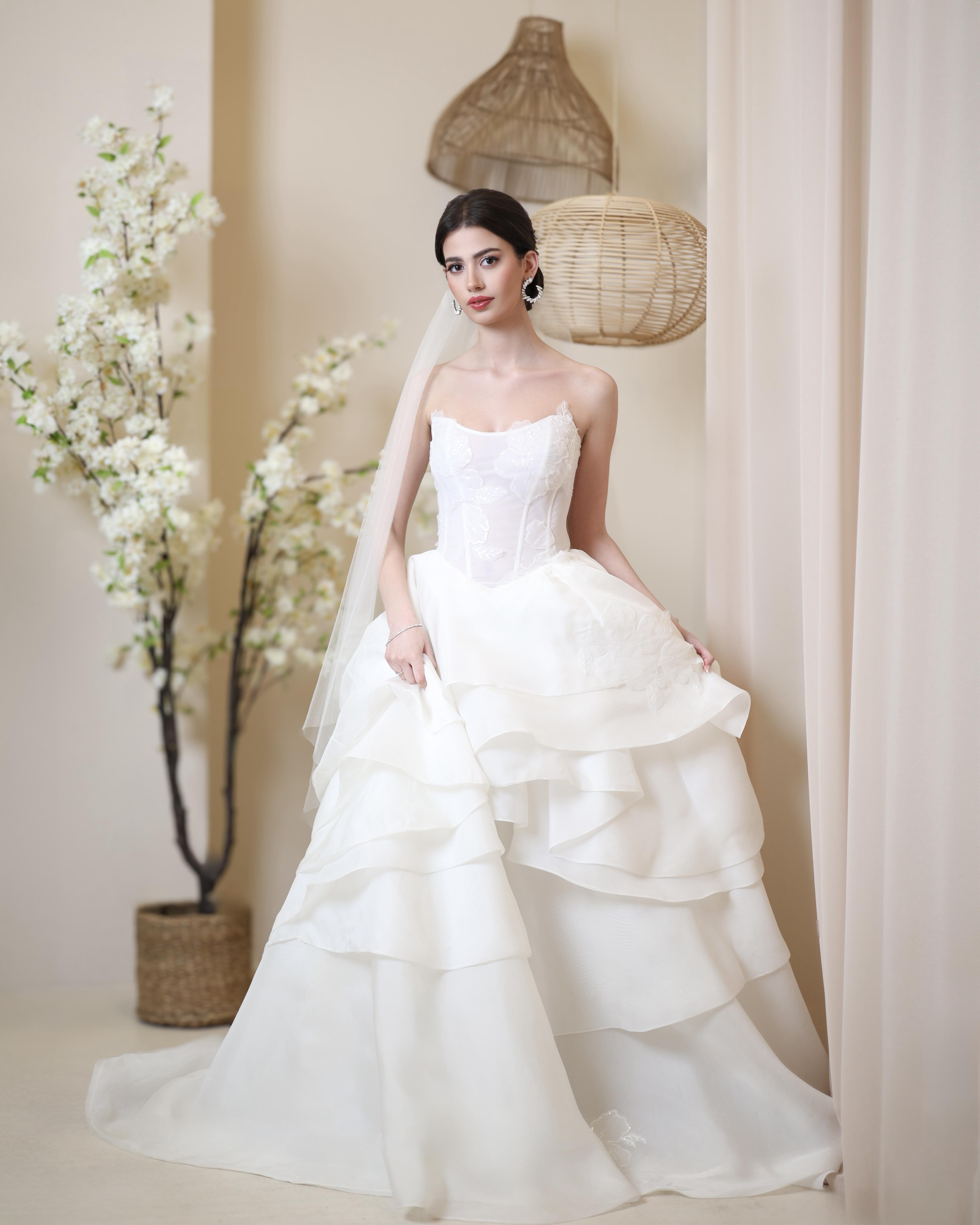 Woman in a white wedding dress standing in a softly lit room with decorative elements.