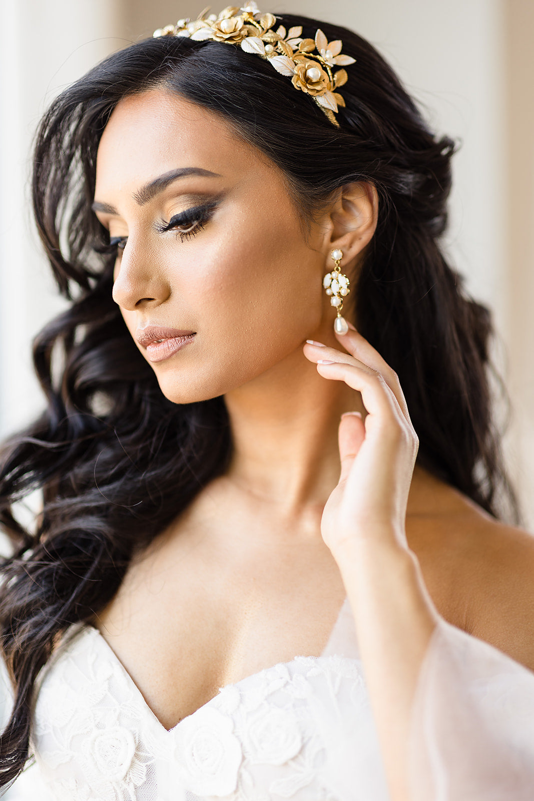 Woman wearing a gold headband and earrings with a blurred background