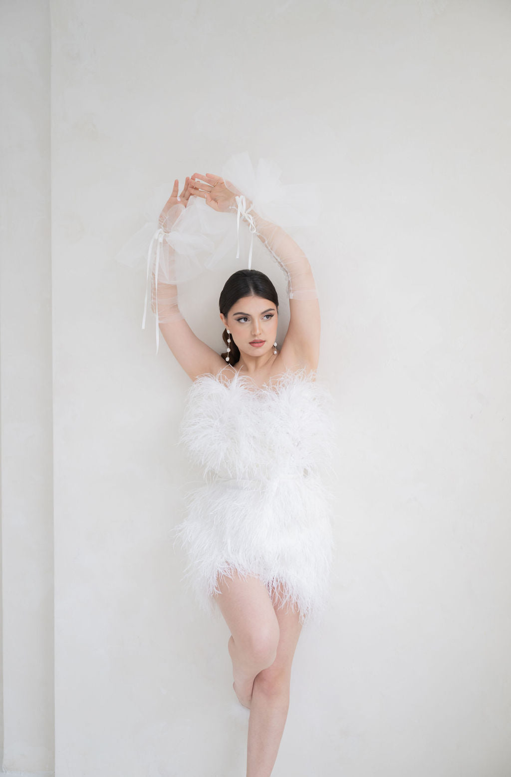 Woman in a feathered dress against a white background