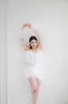 Woman in a feathered dress against a white background