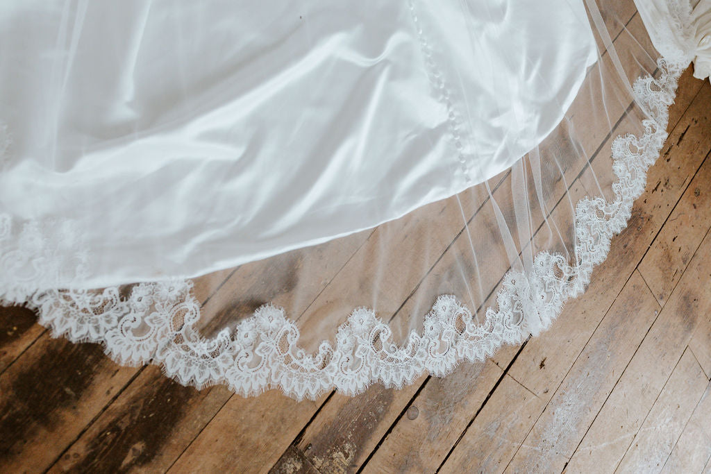 White wedding dress with lace trim on a wooden floor