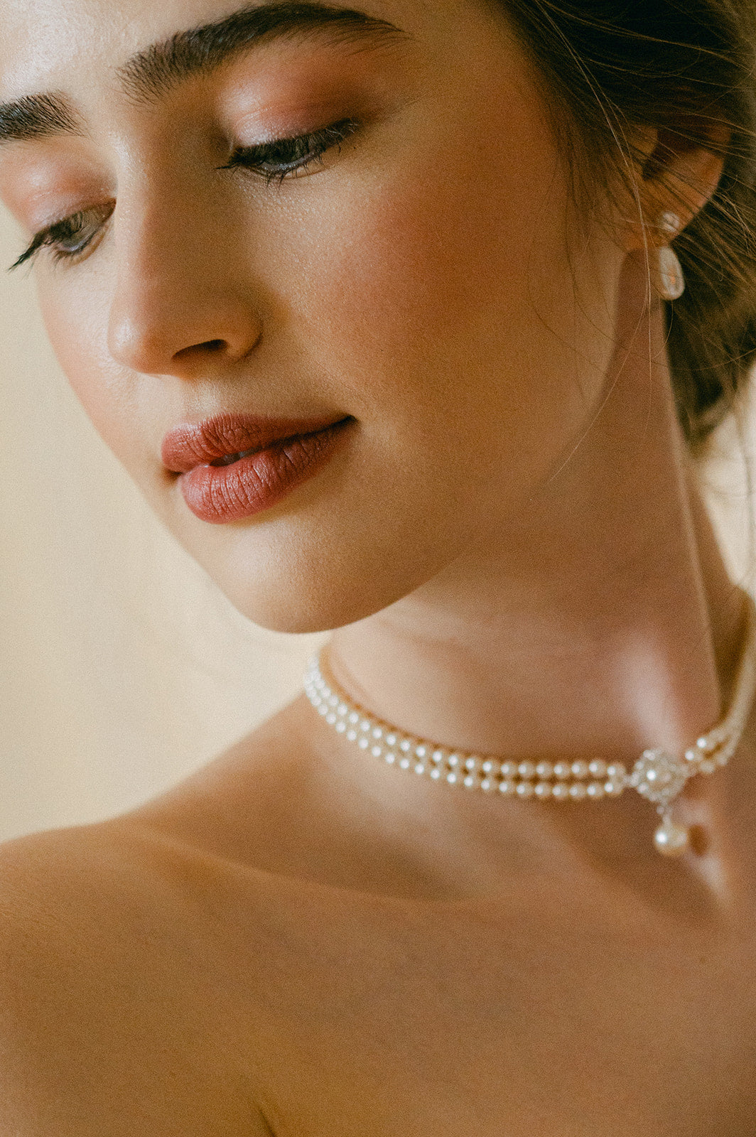Close-up of a woman wearing a pearl necklace with a neutral background