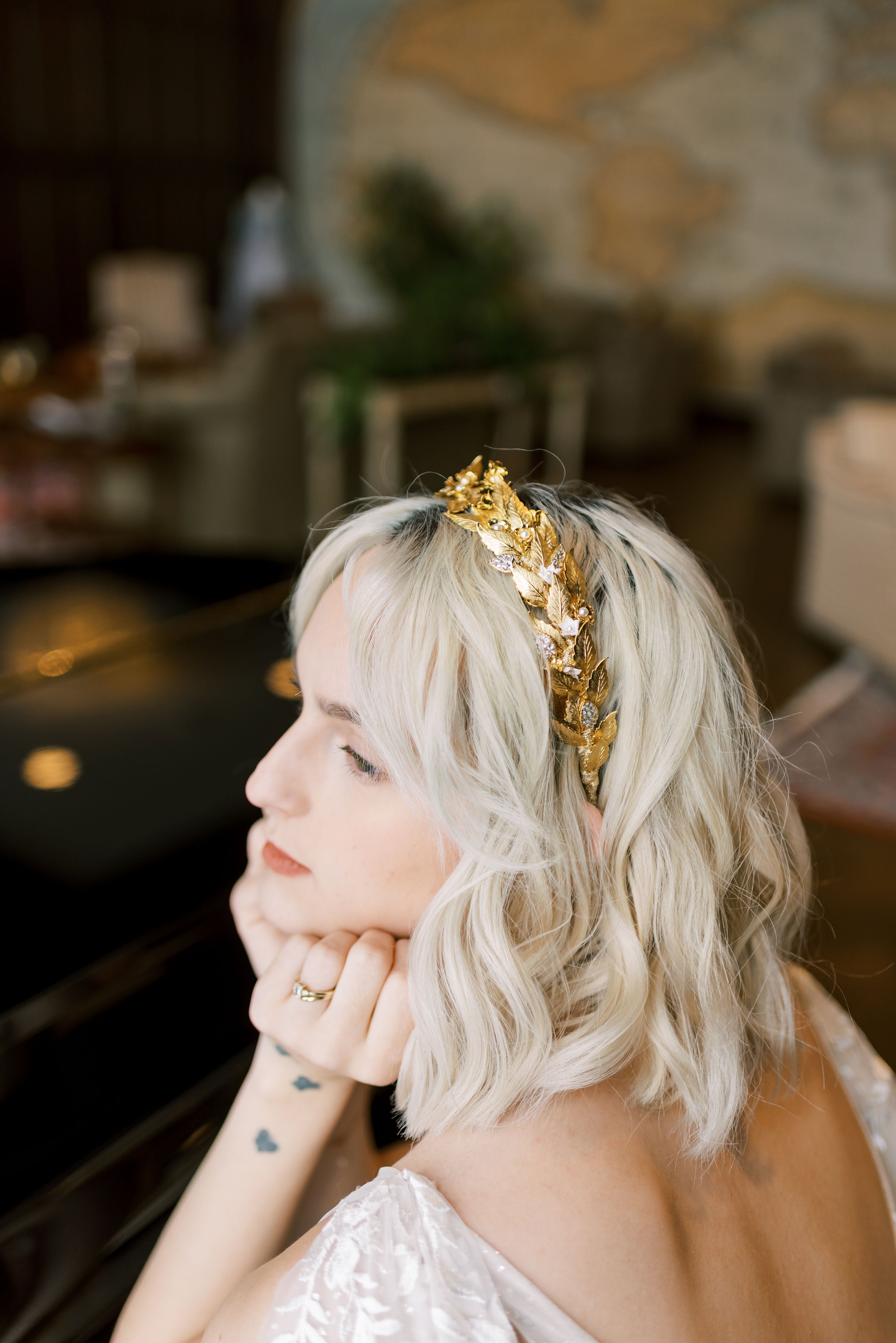 Woman with blonde hair wearing a gold headband in an indoor setting