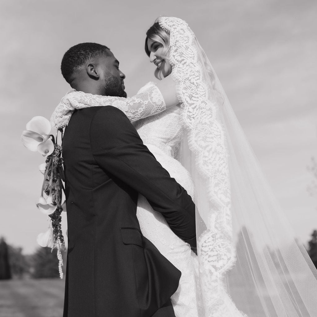 Black and white photo of a bride and groom embracing outdoors.