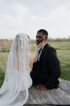 Couple in wedding attire sitting on a rock outdoors
