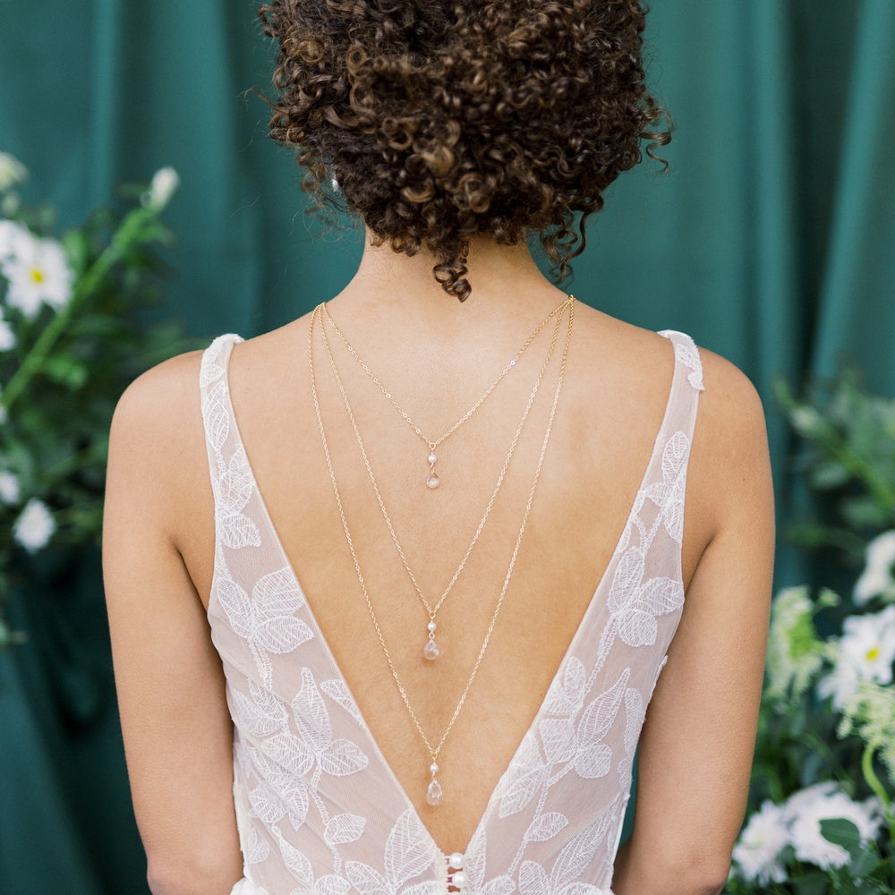 long 3 tiered bridal back necklace for open back wedding dresses. Tiers of crystal and pearl pendants from 10mm to 16mm each linked with a pearl. Simple choker style necklace at front with single pearl. Gold, Rose Gold and Silver and multiple sizes.