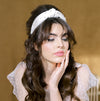 Ivory velvet headband top knotted and hand beaded with round glass pearls in various sizes. Hand sewn to a wide plastic headband that is wrapped in grosgrain ribbon. Handmade in toronto ontario canada by Blair Nadeau Bridal Adornments