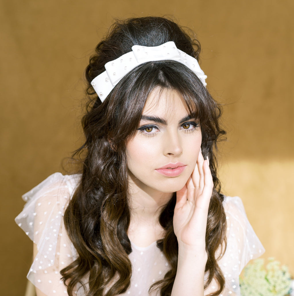 layered ivory or off white grosgrain ribbon hair bow hand stitched to create a layered affect with hand beaded round glass pearls in various sizes on each layer of bow.  small pearls on top layer to large pearls on bottom layer. stitched to headband.  Handmade in Toronto Canada by Blair Nadeau Bridal Adornments