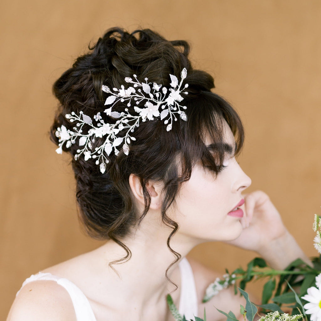 extra long and extra wide bridal hair vine with sprigs of rhinestones, clear crystal beads, pearls and navette crystals. hand painted leaves throughout with hand sculpted flowers along the vine. Available in silver or gold with white or ivory flowers Made in Toronto Canada by Blair Nadeau Bridal Adornments